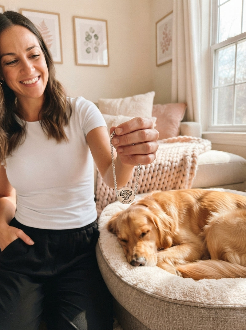 A woman holds a personalized pet bracelet near her sleeping golden retriever in a sunlit home.